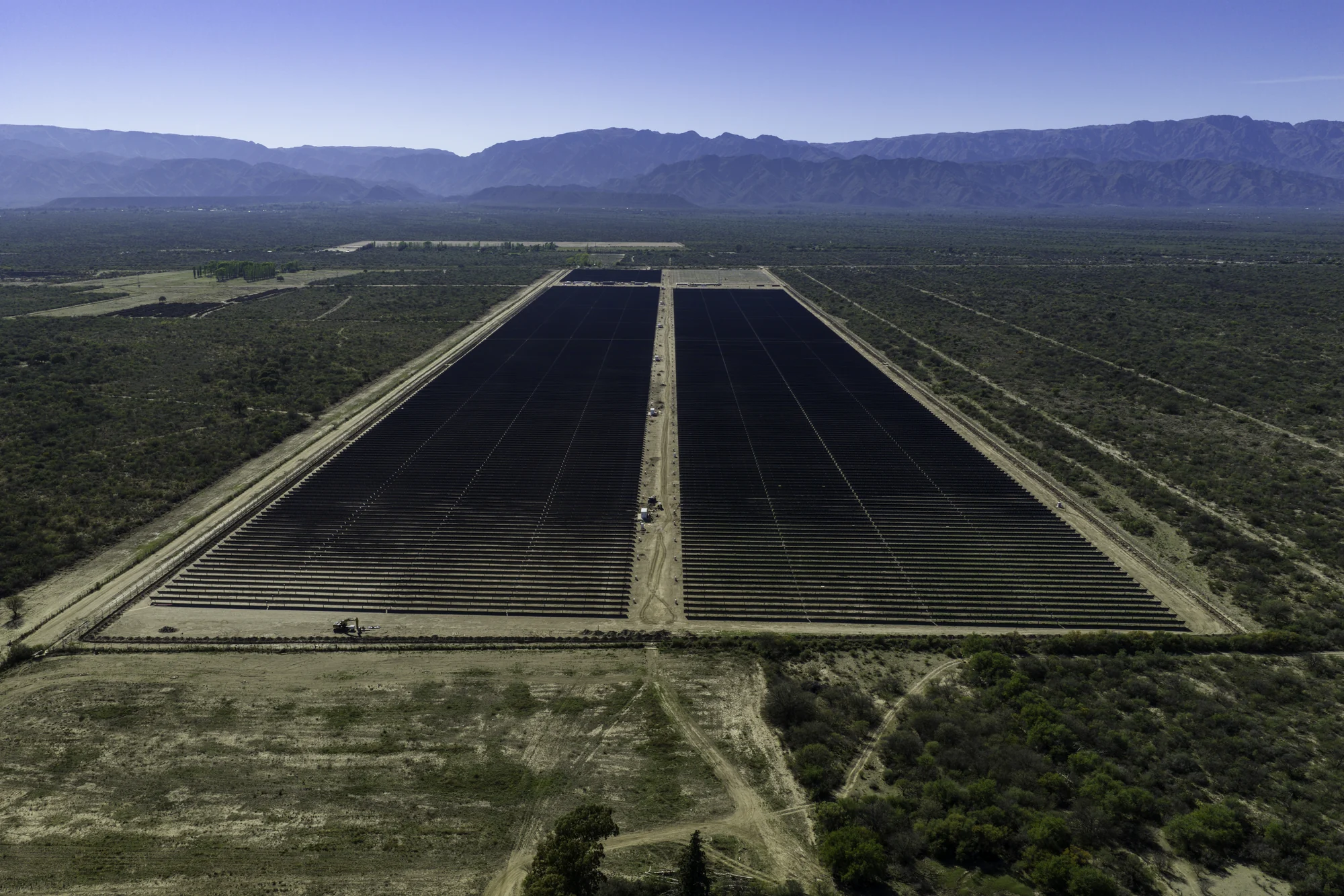 Vista frontal aérea de las filas solares de Calicanto a ambos lados del camino central.